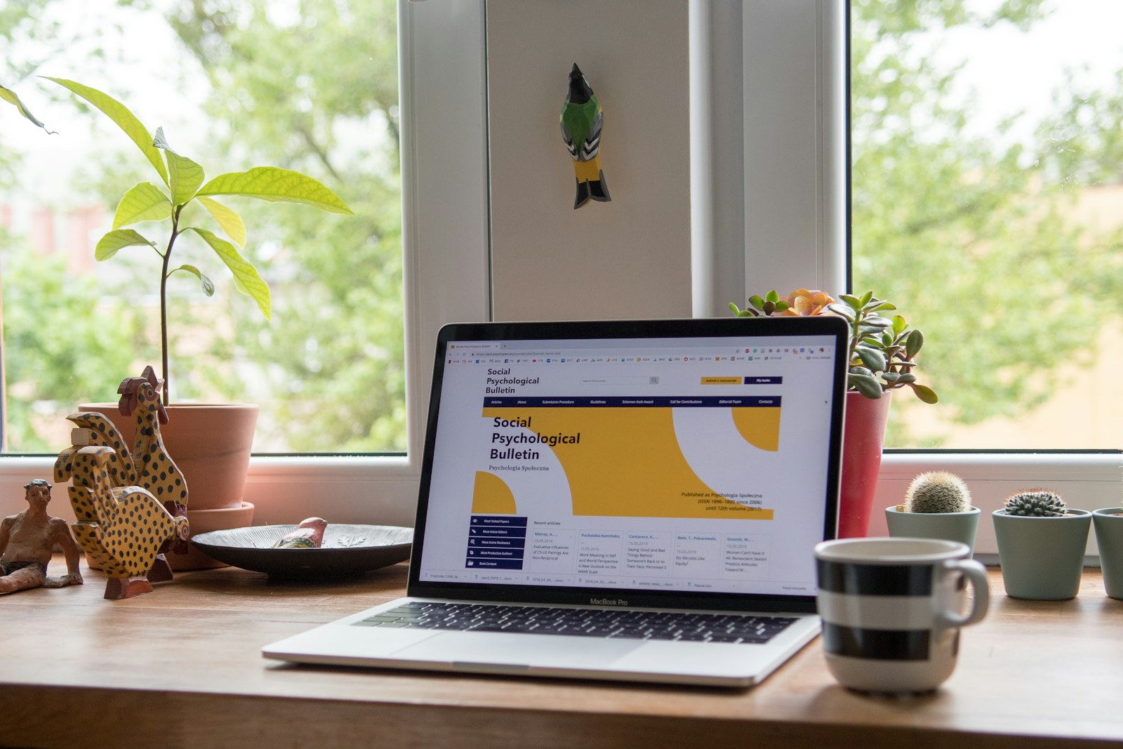 A laptop displaying a website on a wooden desk with potted plants