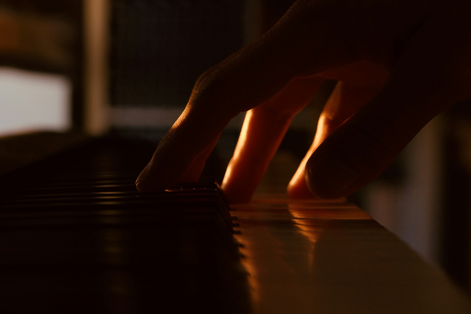 Fingers playing piano keys in warm light