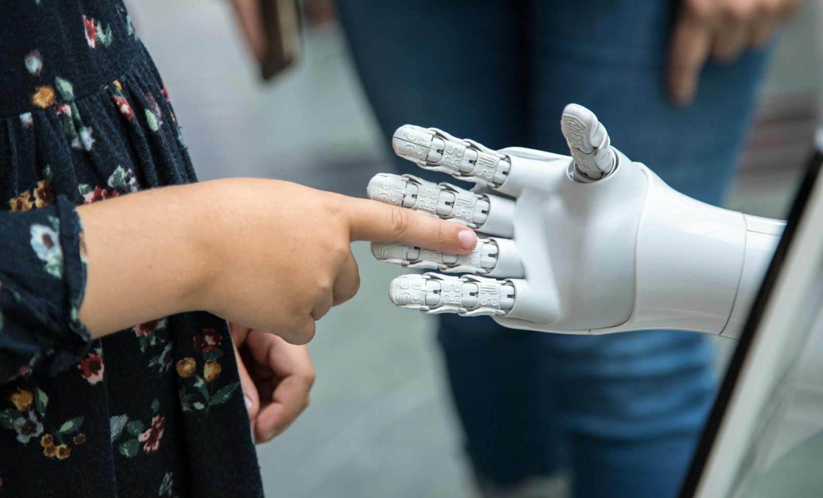 A child touching the finger of a white robotic hand
