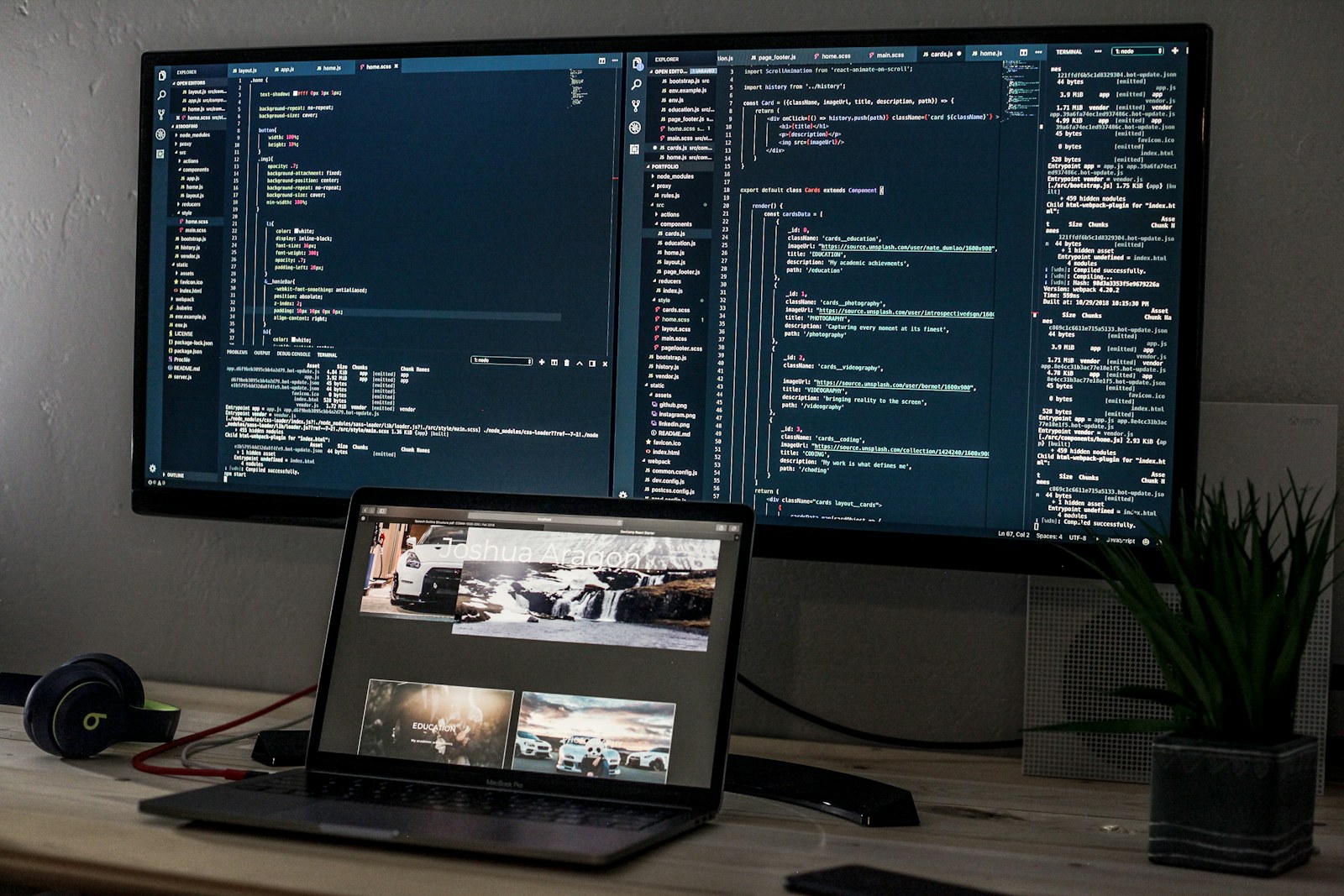 A laptop and a wide monitor displaying lines of code on a desk