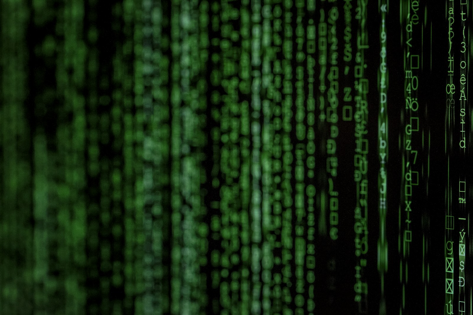 Vertical columns of glowing green digital code against a dark black background
