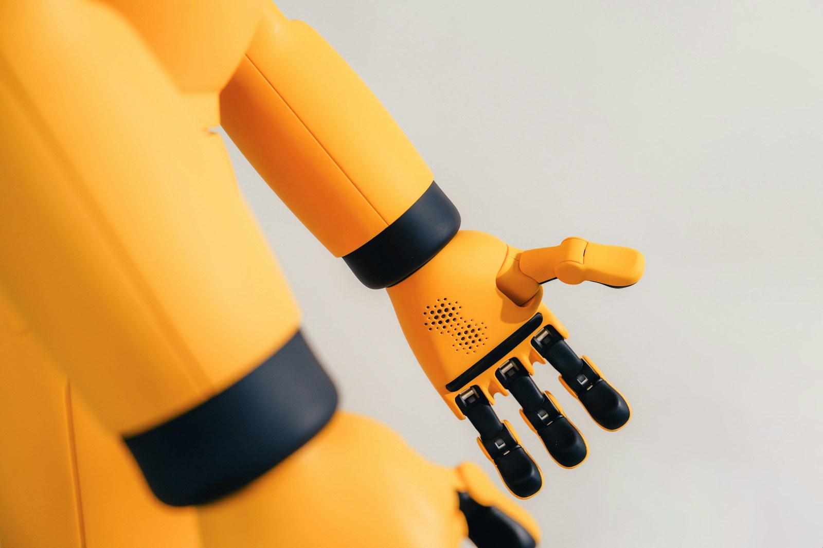 A yellow robotic arm with black joints and a mechanical hand