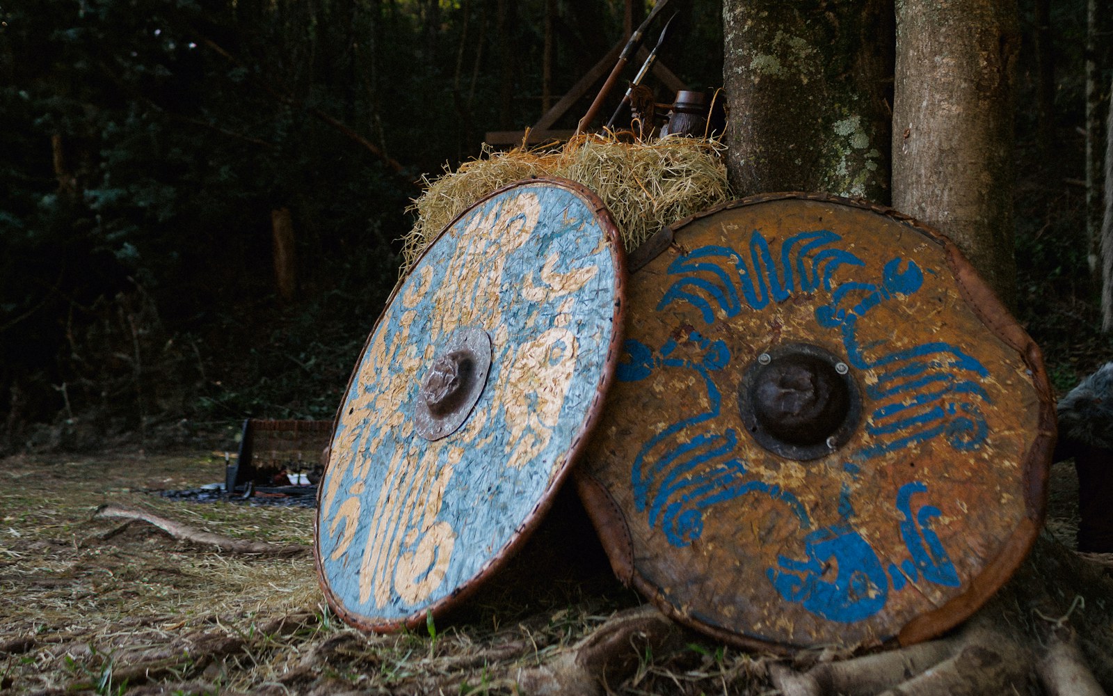 A pile of hay sitting next to a forest filled with trees