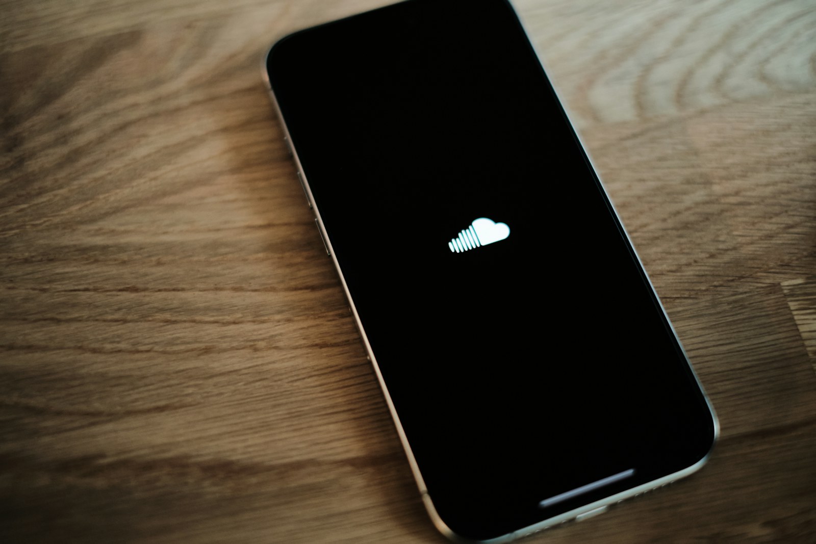 An iPhone sitting on a wooden table with an apple logo on it