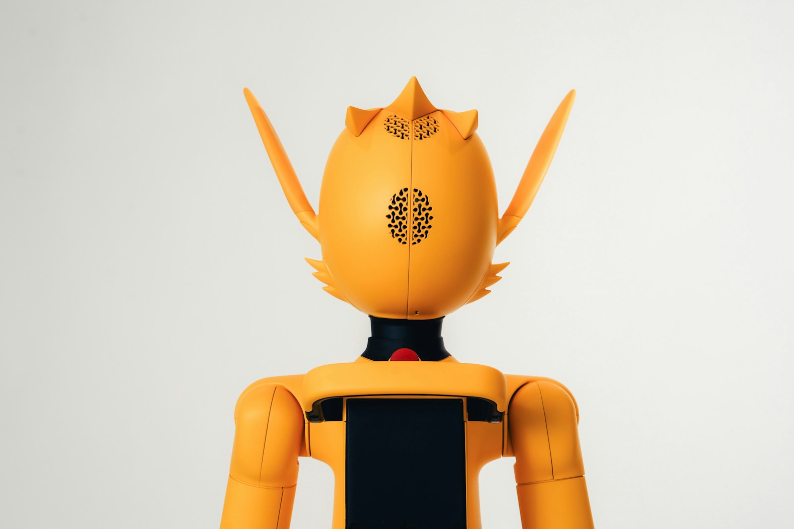 Back view of an orange robot with pointed ears and speaker grilles
