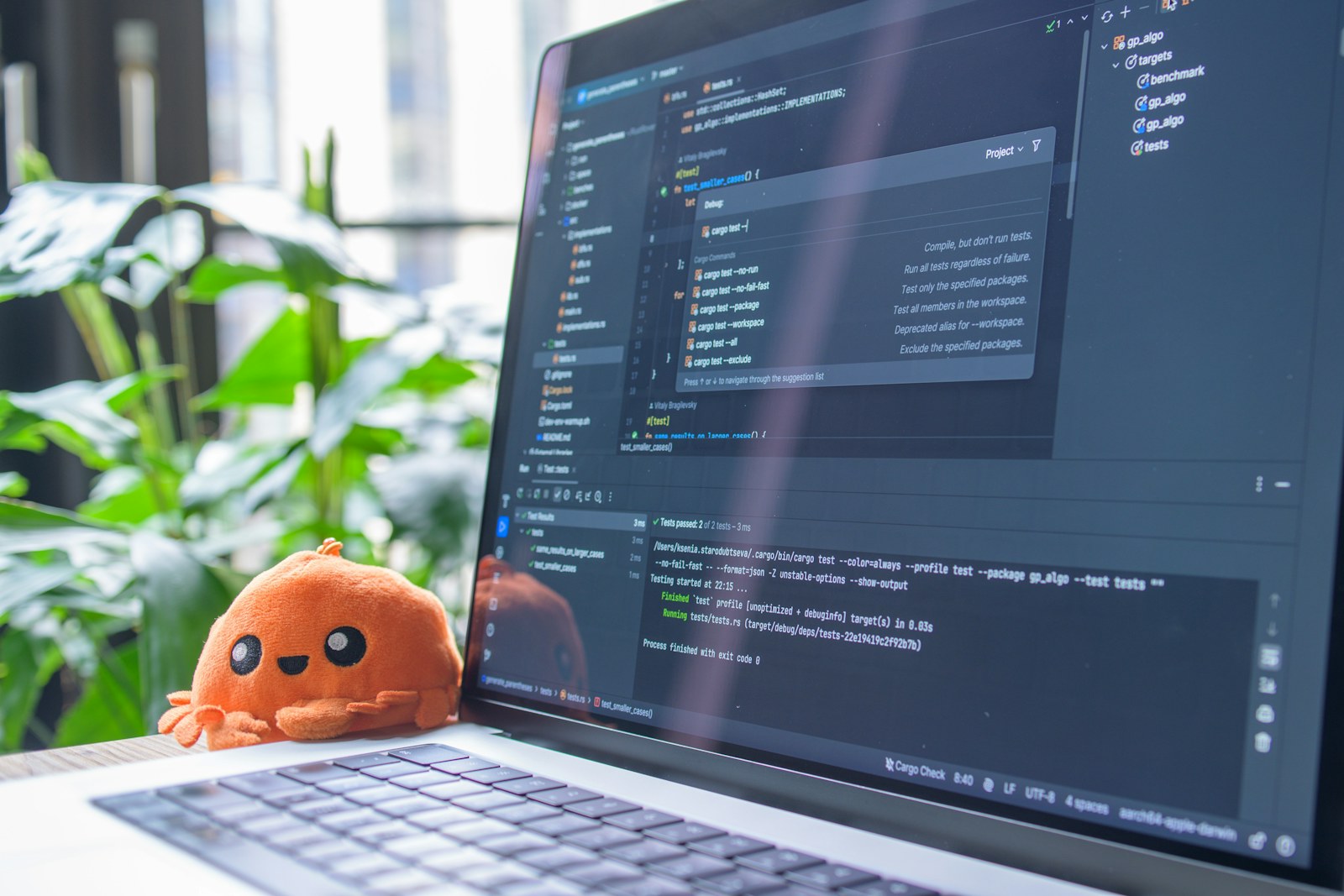 Laptop screen displaying code with a small plush toy