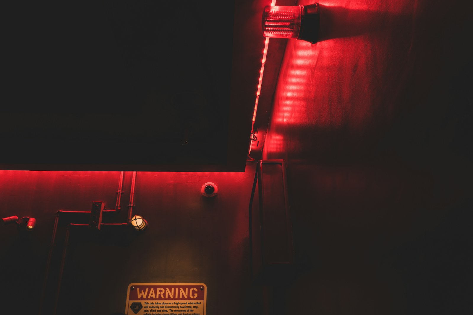 a dark room with a red light and a warning sign