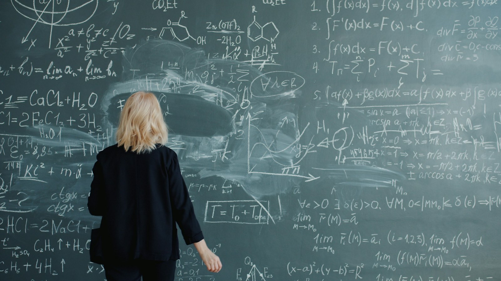Woman looking at a blackboard with complex math equations